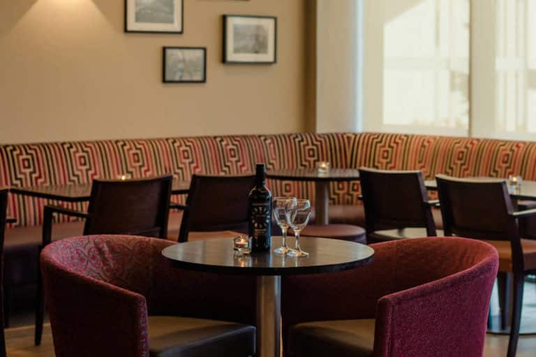 Een fles rode wijn voor twee aan een gezellige tafel in The Lodge Bar Rochestown Lodge Hotel