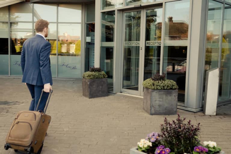 Guest with suitcase entering the front entrance of Rochestown Lodge Hotel Dun Laoghaire