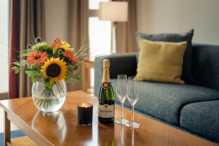 PREMIER SUITES Dublin Sandyford living room couch and wine with glasses and flowers