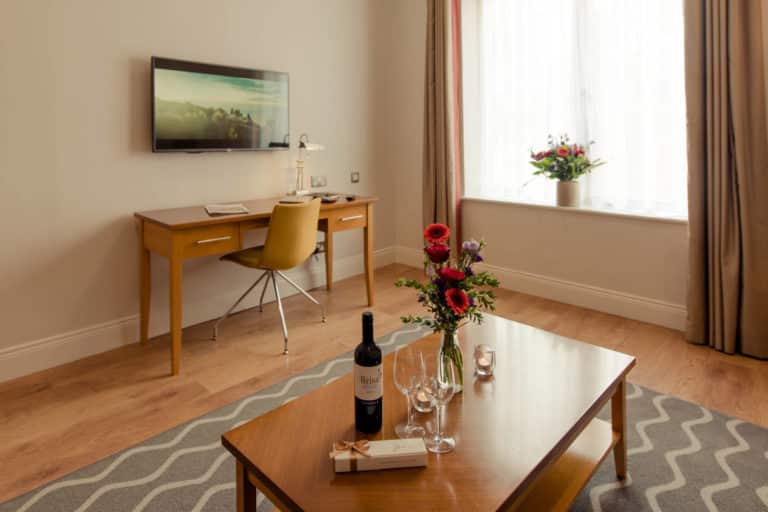 PREMIER SUITES PLUS Dublin Leeson Street table with wine and flowers on carpet in front of tv_ one bed